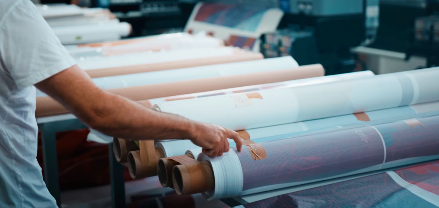 The design is printed onto paper before being transferred onto the canopy material. Ralf points to a printed paper roll before it's transferred to the kite fabric.
