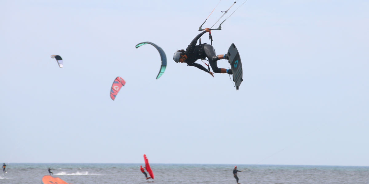 You can't always keep your eyes on your kite, so it's important to be able to feel where it is. A kiteboarder jumps with the kite behind his back.