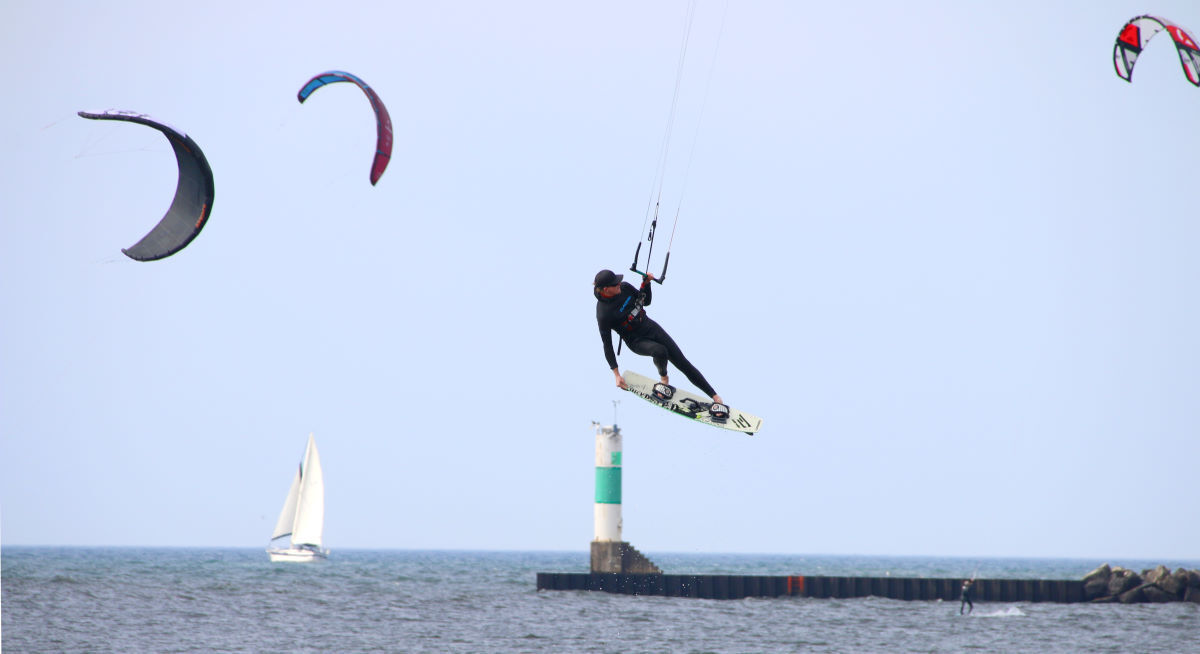 Many tricks require you to be able to fly one-handed. A kiteboarder jumps while controlling the kite with one hand.
