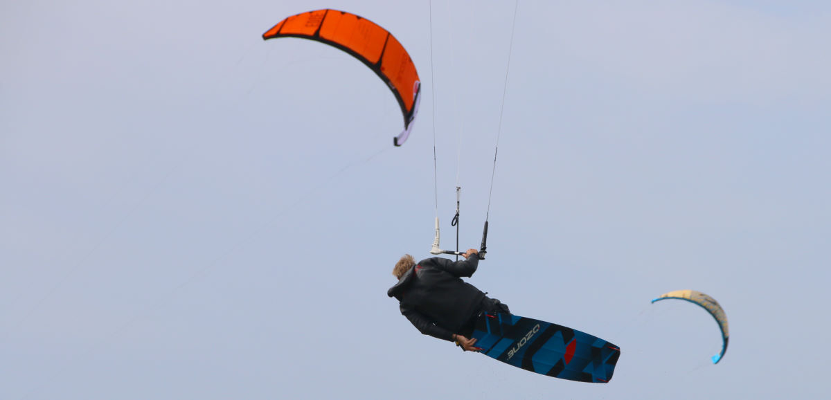 Is light or heavy bar pressure better for you? A kiteboarder jumps while controlling the kite with one hand.