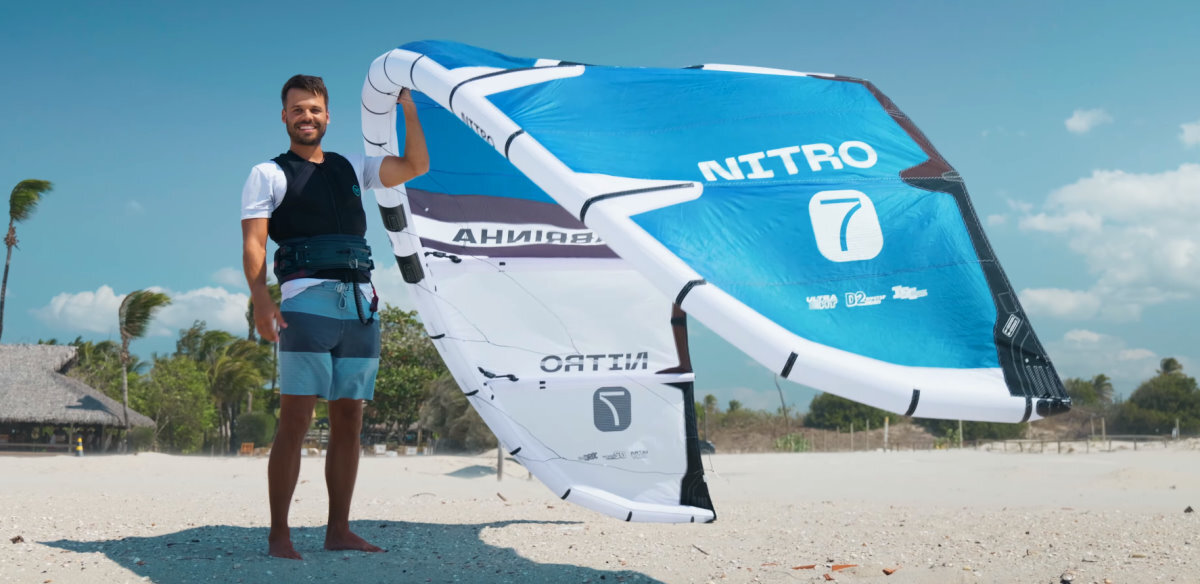 Rubens stands on the beach, holding a Nitro kite