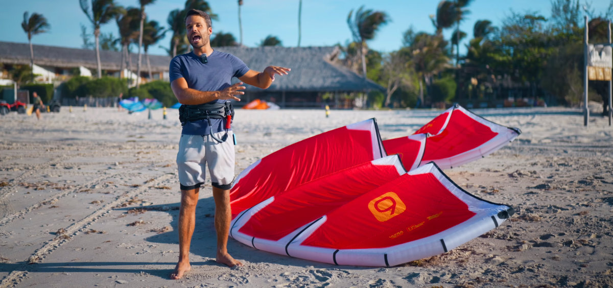 A kiteboarder stands next to his Nitro kite on the beach.