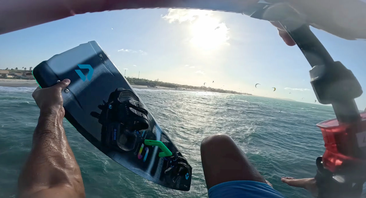 A kiteboarder takes his board off mid-air.