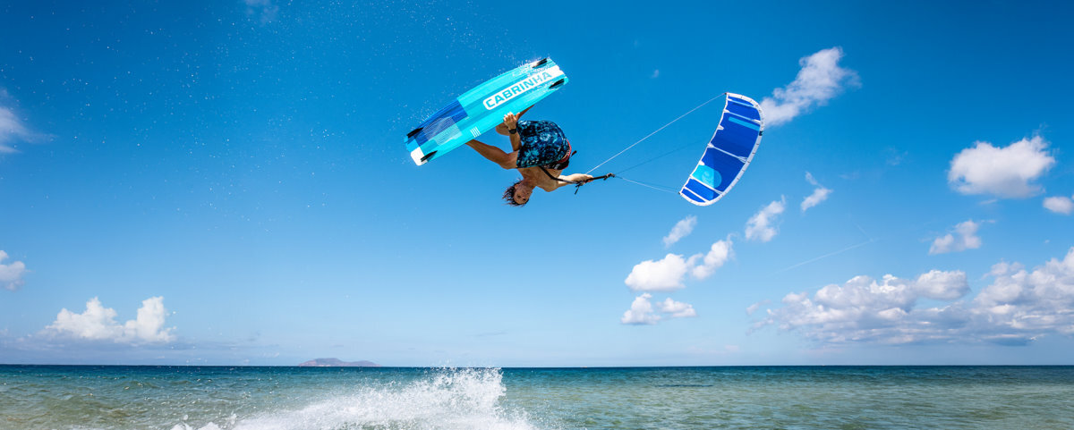 A skilled kiteboarder performs a board grab trick.