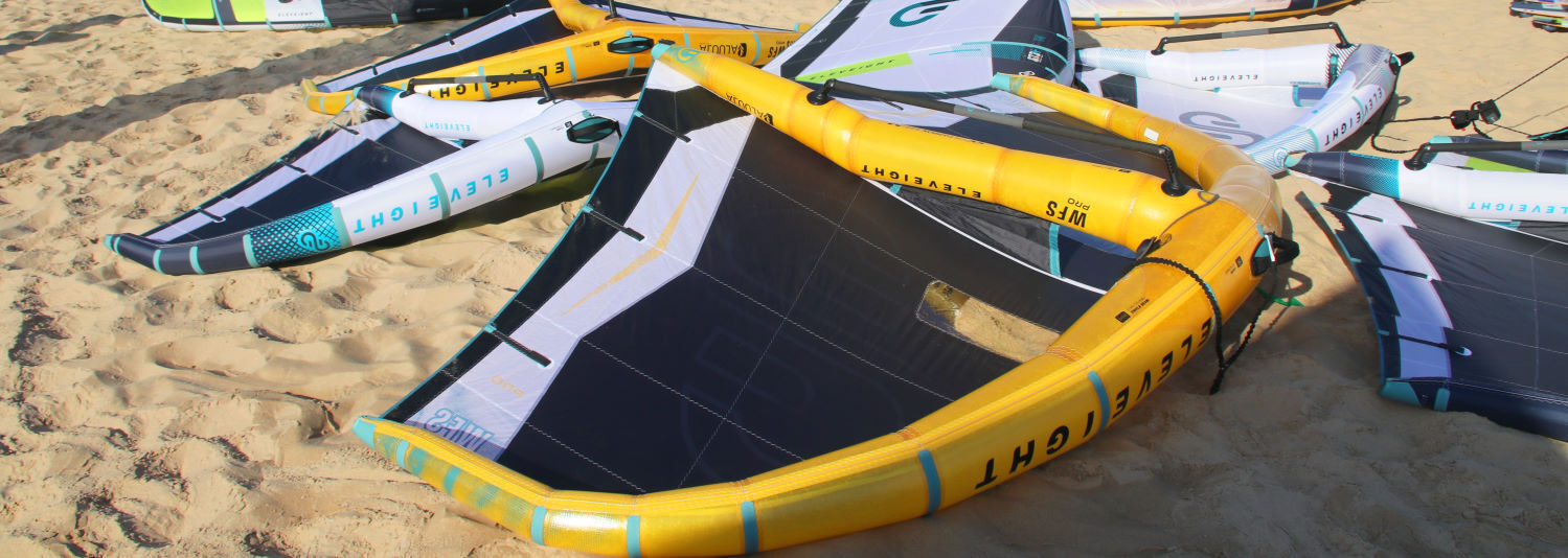 Eleveight wings sit on display at the beach. Two have Aluula frames.
