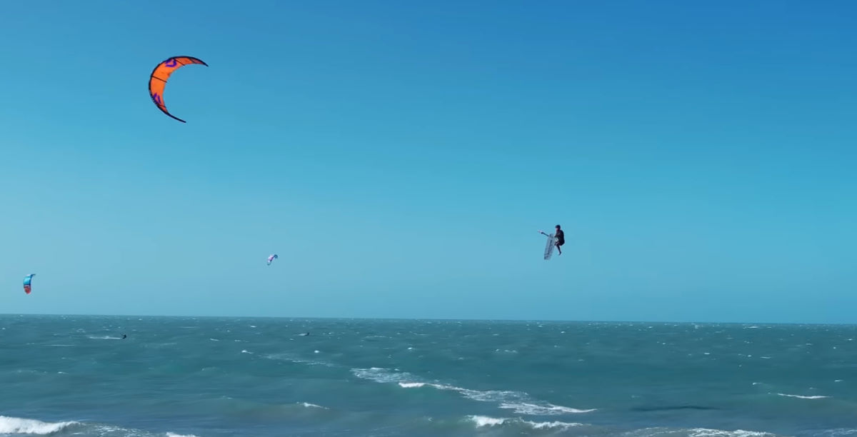 A kiteboarder takes his board off during a jump.