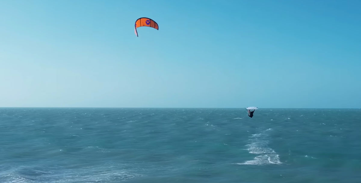 A kiteboarder is upside-down in the air after jumping.