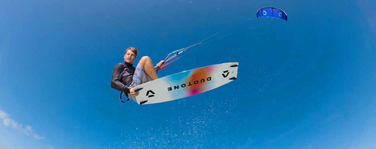 A kiteboarder jumps high into the air.