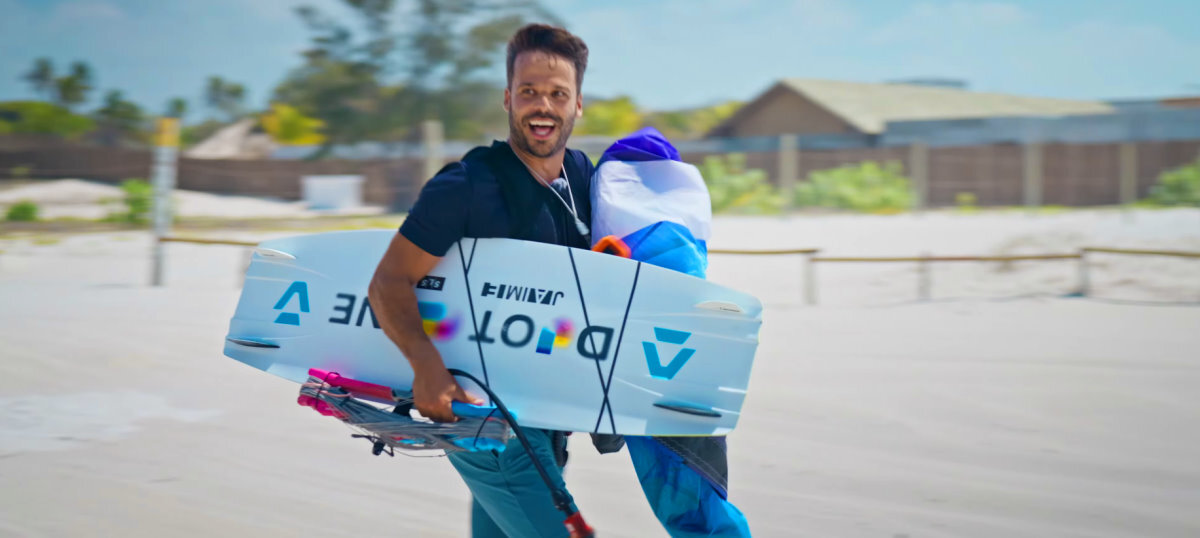 Rubens is ready for a great testing session! A kiteboarder walks across the beach carrying his gear.