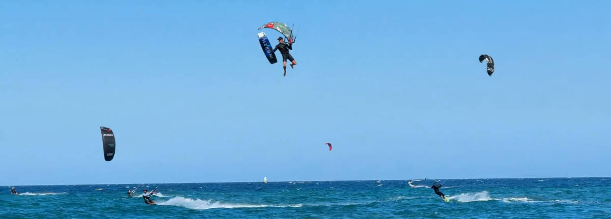 David takes his board off his feet mid-jump while kiteboarding.