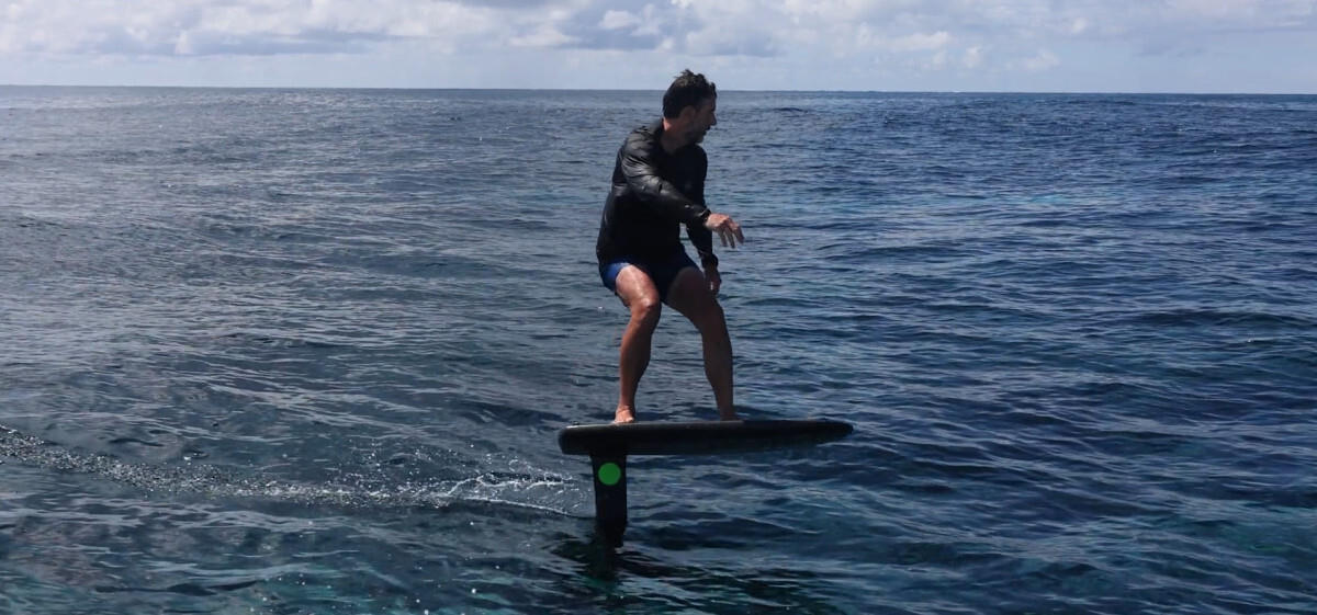 A surfer rides a small wave on an AMPJet board.