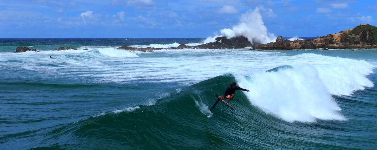 A surfer rides a wave with an AMPJet board.