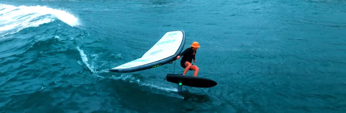 A wing foiler surfs a wave using the AMPJet.