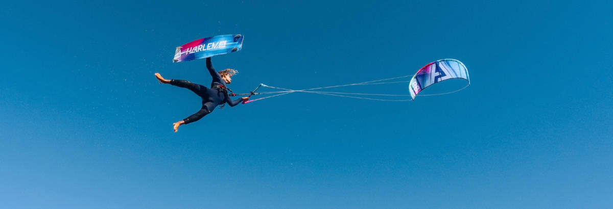 A kiteboarder performs a trick in the sky.
