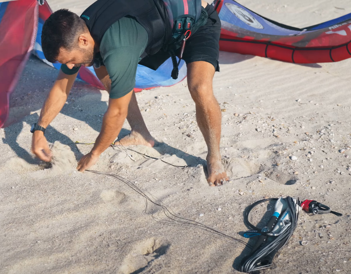 And a little more sand on the lines. A kiteboarder weighs his lines down with sand.