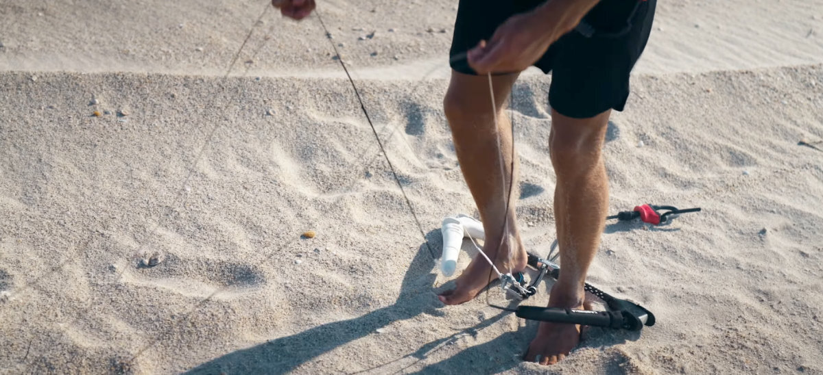 You can use your hands and legs to separate 4 lines at once. A kiteboarder demonstrates how to separate your lines during setup.