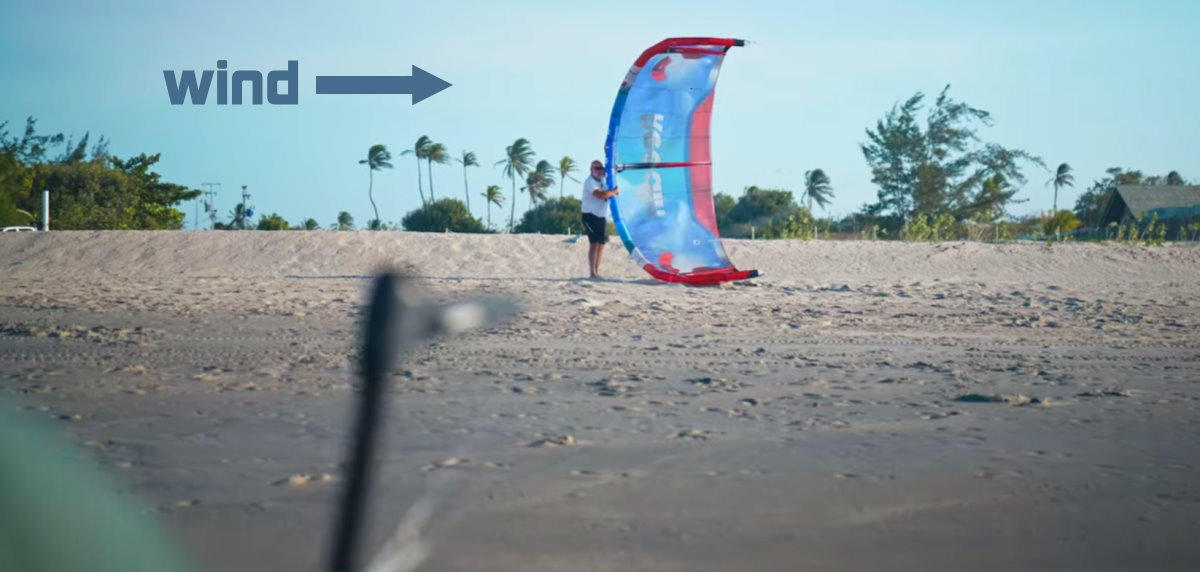 Move to where the air is just starting to fill your kite. A kiteboarder stands in the launch area while his assistant holds his kite in the launch position.