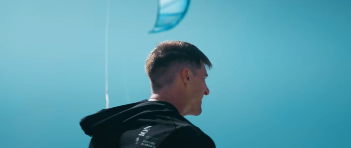 Aaron's in Brazil and ready to boost! Aaron Hadlow stands on the beach, ready to go ride.