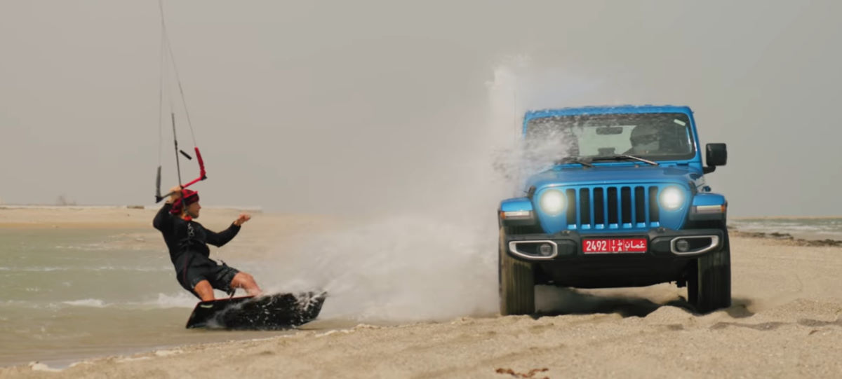 Stig rides beside a Jeep driving on the beach during a commercial shoot.