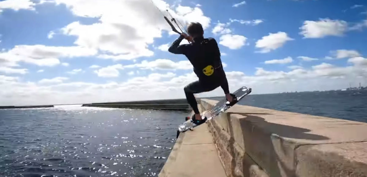 Nick Jacobsen slides his kiteboard across a breakwater wall.