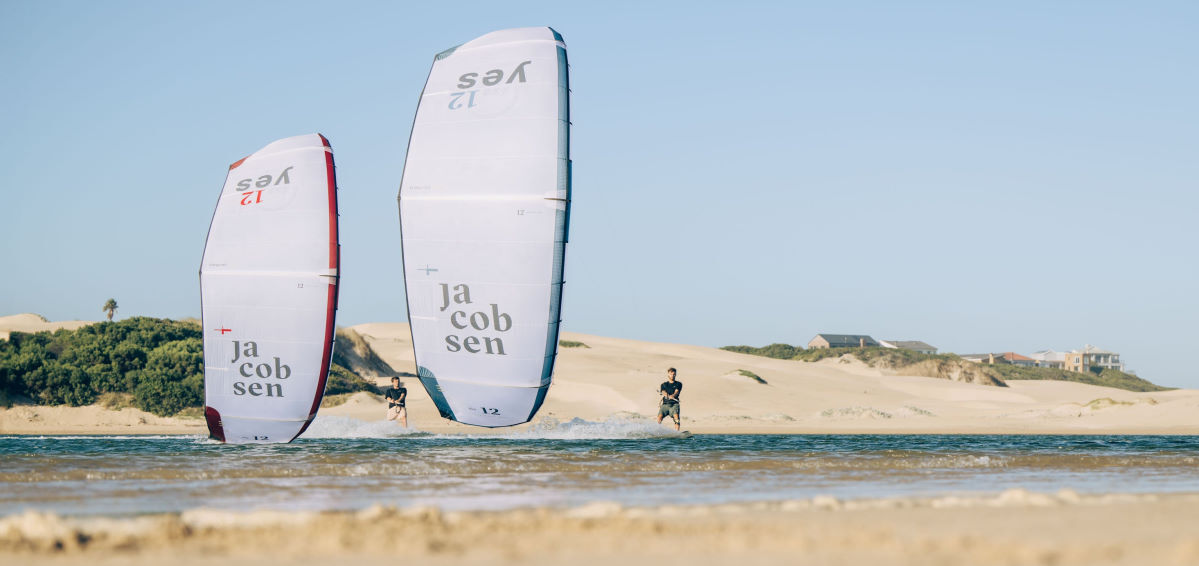 Two kiteboarders ride side-by-side with Yes kites.
