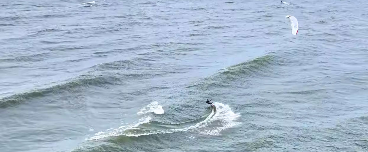 Jeff kitesurfs a wave with a twintip and the Jacobsen Yes kite.