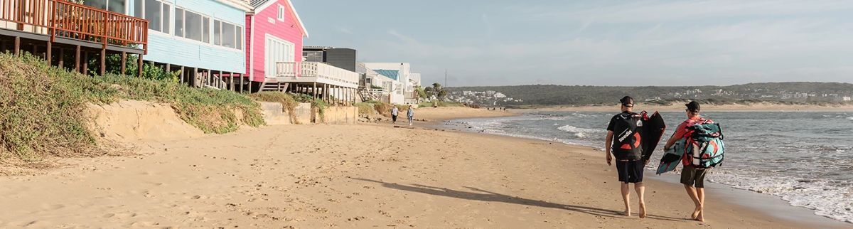 Kevin and Damien walking with kite gear along the beach