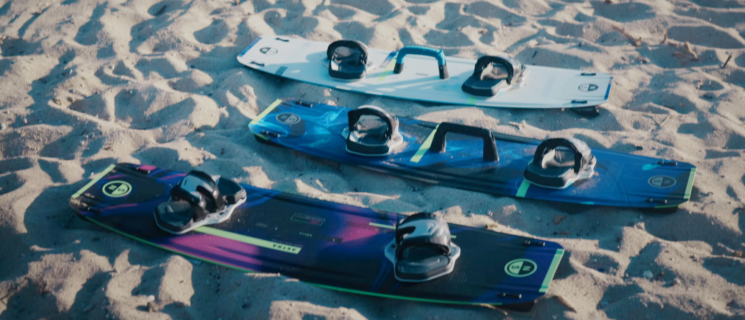 Which new North twintip is right for you? The Astra, Atmos, and Atmos Pro boards on the beach in a row.