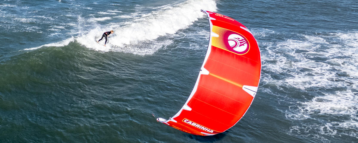 A kiteboarder rides a wave with the Cabrinha Drifter.