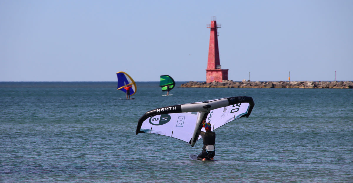 A wing foiler gets ready to ride, their knees facing forward.
