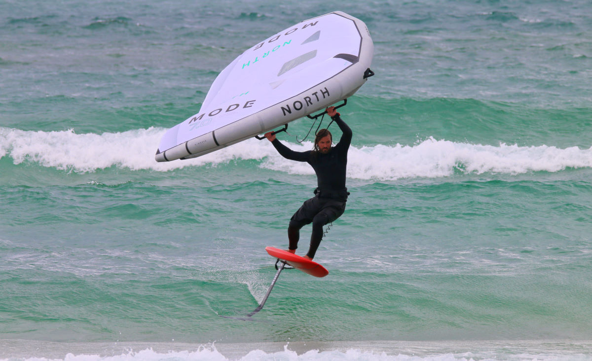 Tucker wing foils down a wave.