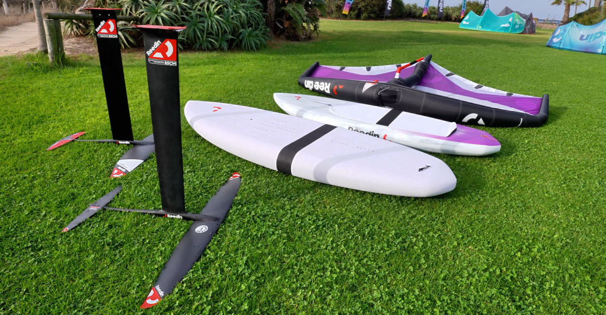 The components of the package-wing, board, and foil, lay on the grass.