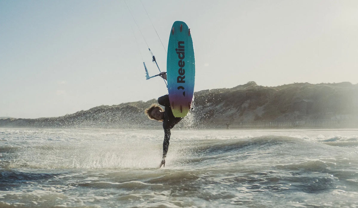 A kiteboarder jumps and drags his hand in the water.