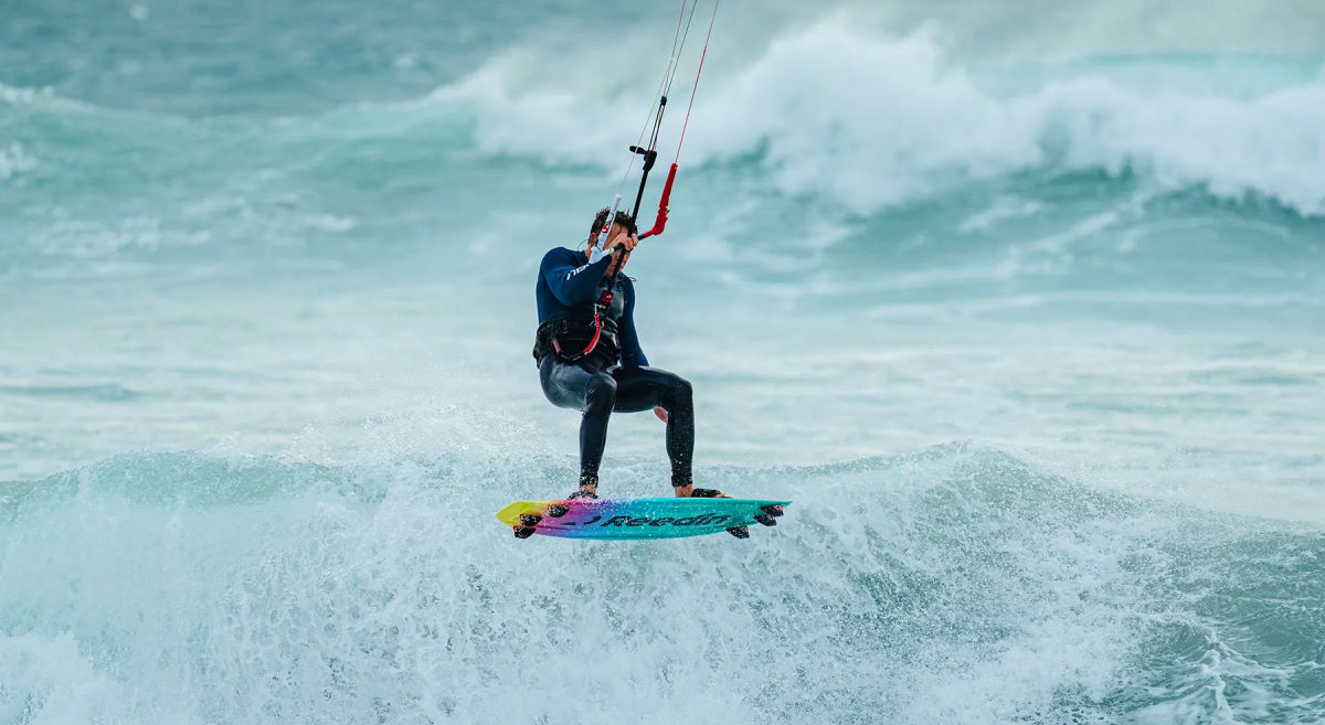 A kiteboarder jumps near a wave.