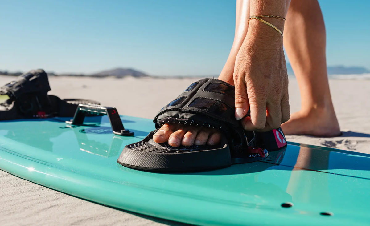 A kiteboarder slips their foot into the bindings on the SnackPack.