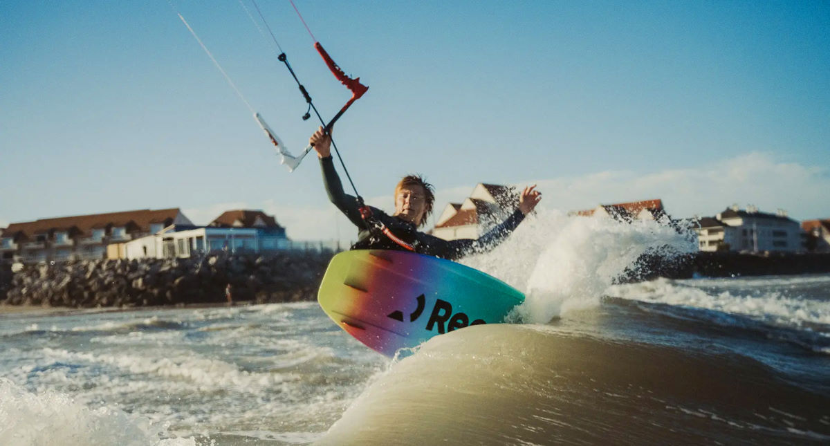 A kitesurfer carves on a wave.