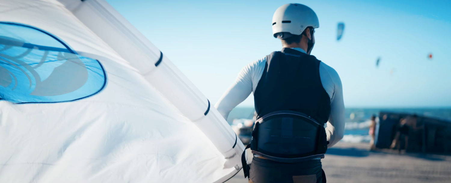 An impact vest is an essential part of your gear, and the Empax is a good option. Rubens heads toward the water holding a kite and wearing the Empax vest.
