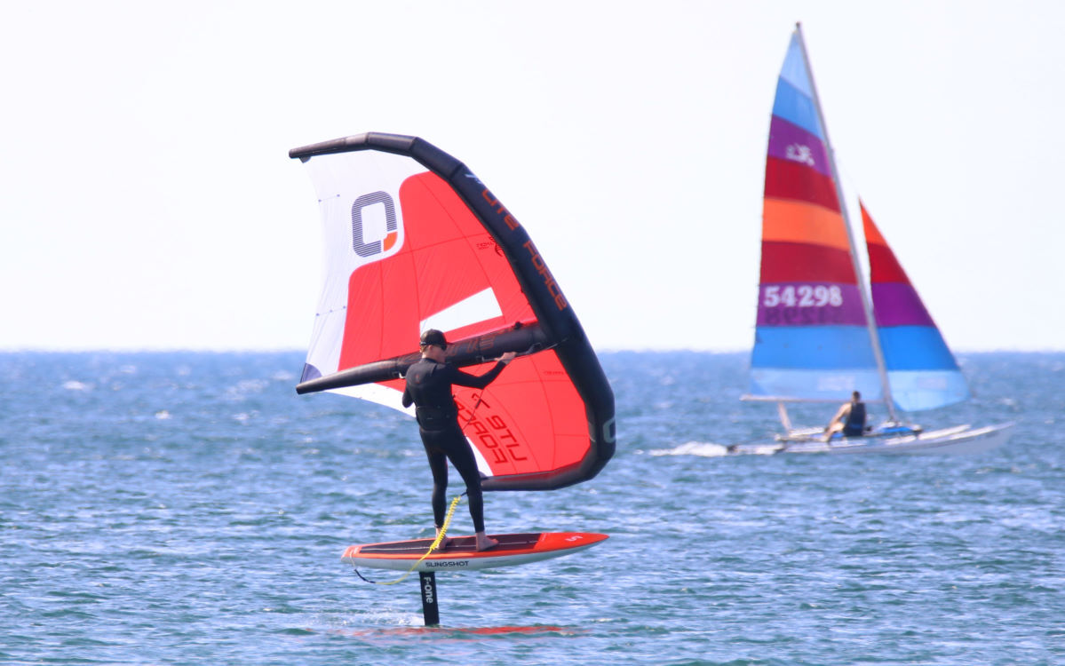 Jeff wing foils, his right foot forward.