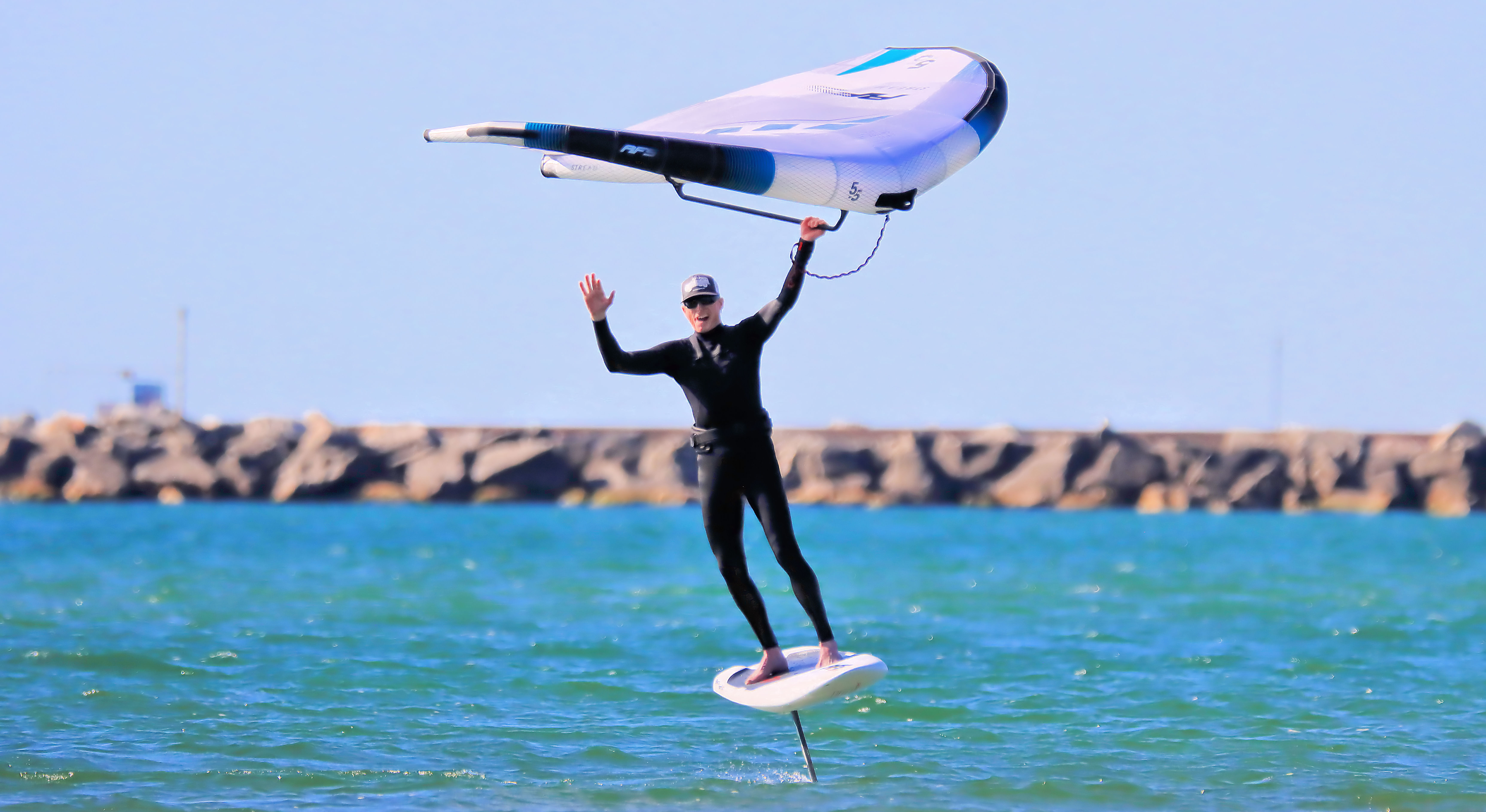 Jeff waves while wing foiling.