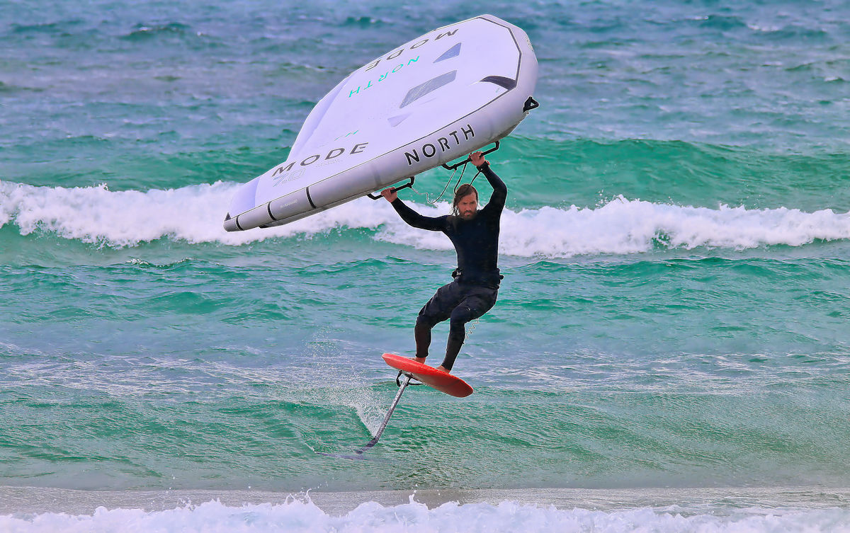 Tucker wing foils down a wave.